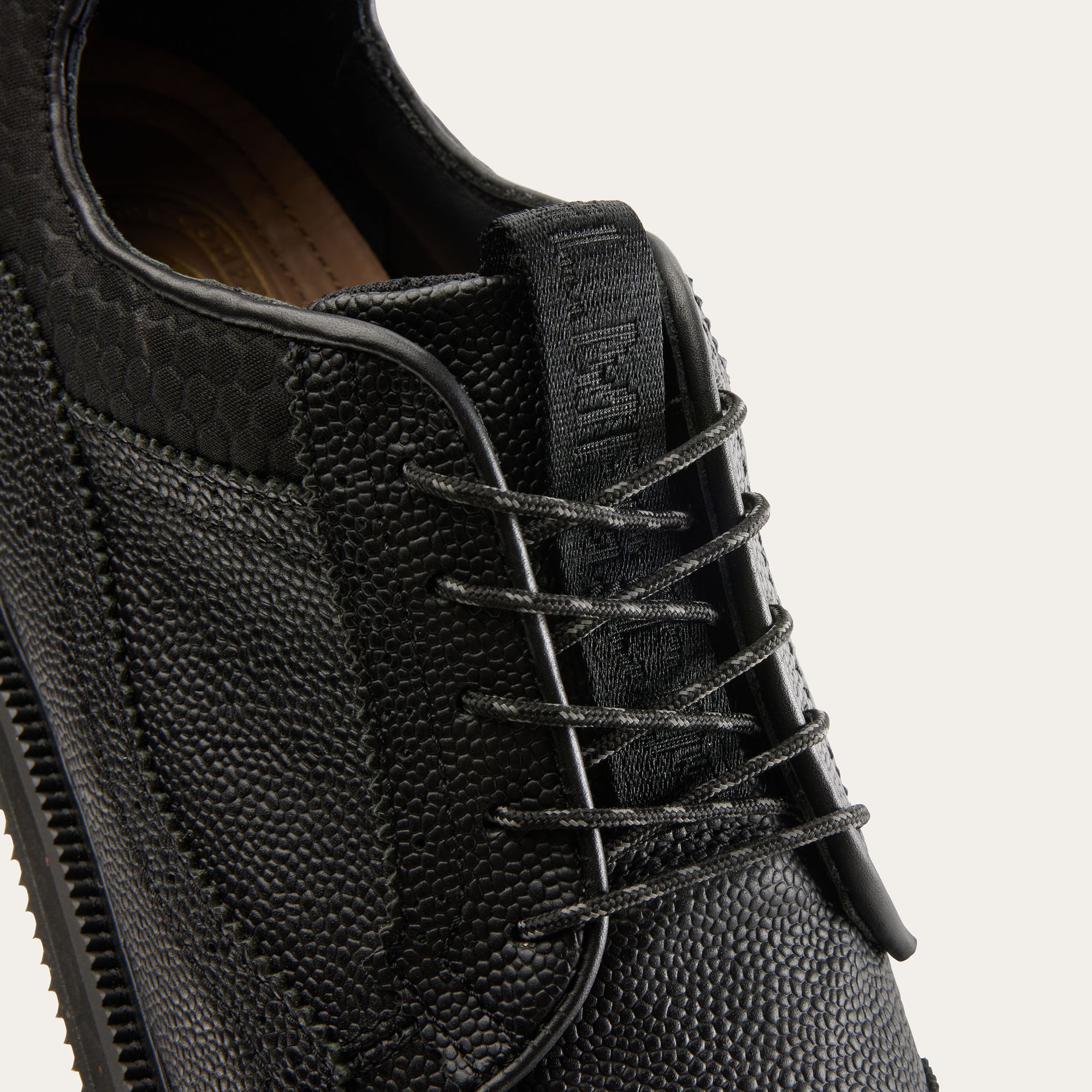 Close-up of GL1 BLACK golf shoe's black leather pebble grain leather and laces.